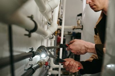 Technician inspecting commercial plumbing pipes in Newark