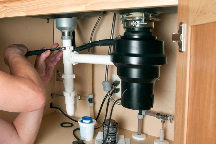 Plumber repairing a garbage disposal in Newark