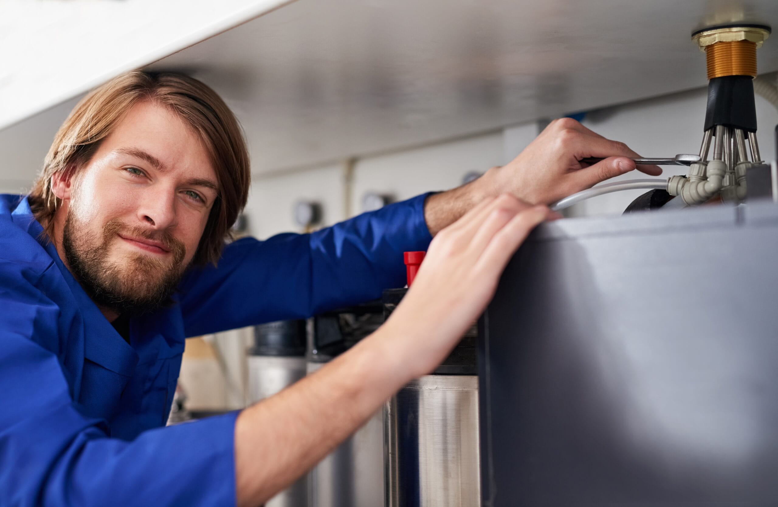 Technician servicing a residential water heater tank in Newark